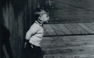 Black and white photo of child with hands behind back